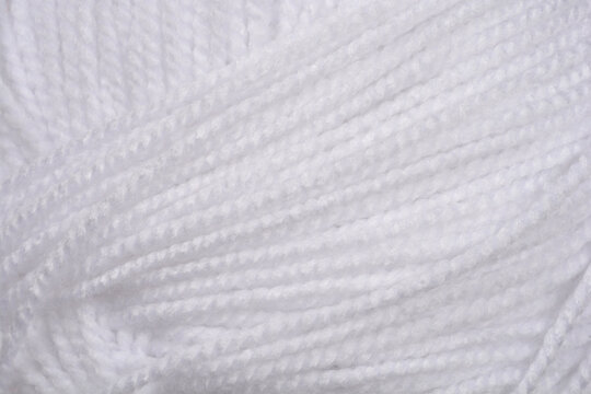 A macro shot captures the soft, fluffy texture of white yarn threads