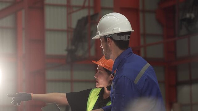 Professional engineers, supervisors and factory workers collaborate on the production floor while reviewing manufacturing operations with digital tablets. Diverse industrial workforce demonstrating te