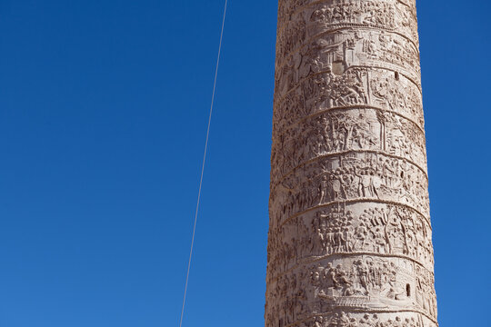 Detailed close up of the ancient Roman reliefs on the Column of Trajan against clear blue sky in Rome, Italy