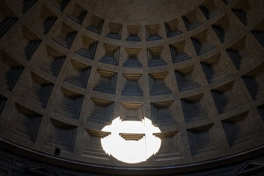 Bright sunbeam light spot projecting onto the ancient coffered concrete dome of the Pantheon in Rome, Italy
