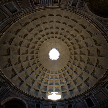 Wide angle panoramic view of the ancient coffered dome of the Pantheon with oculus and light beam reflection in Rome, Italy