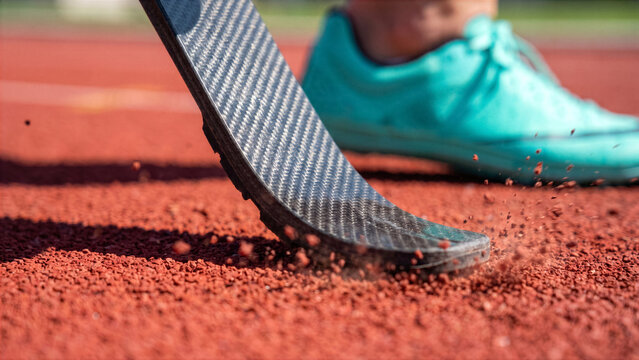 Close up of carbon fiber pattern on adaptive runner blade striking red running track