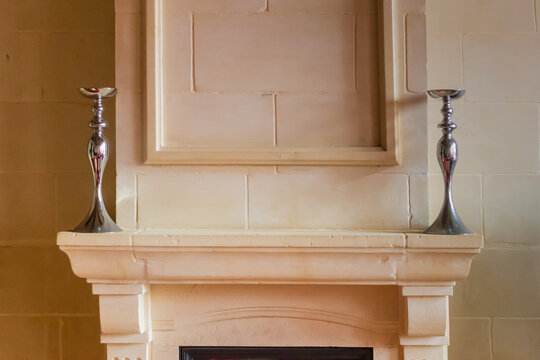 Elegant Stone Fireplace Mantel With Pair Of Modern Silver Candlesticks On Neutral Wall
