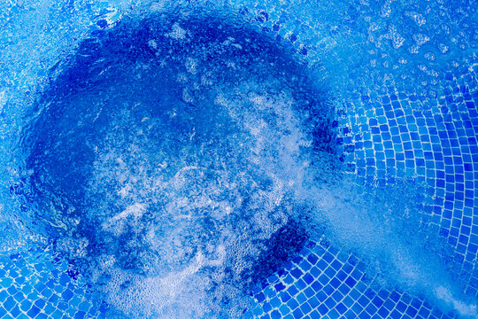 Bubbling Blue Pool Water Over Mosaic Tiles With Whirlpool Jets Creating Foam and Motion