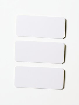 A set of three clean, unblemished rectangular white paper labels, with slightly rounded corners, arranged in a column, isolated on a seamless white background, with soft, directional lighting