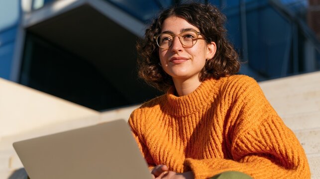 Young Woman with Glasses, Sweater, and Laptop in Outdoor Setting
