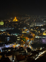 Fototapeta premium City nightscape with illuminated cathedral and glowing streets seen from above.