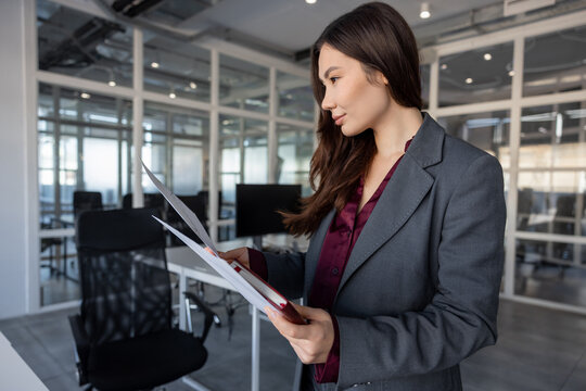 Smiling young woman holding documents in hands and looking contented