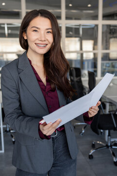 Smiling young woman holding documents in hands and looking contented