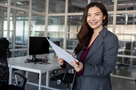 Smiling young woman holding documents in hands and looking contented