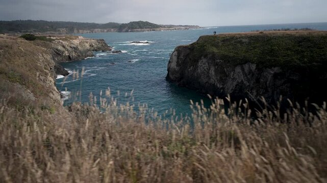 Views of craggy coastlines in Mendocino California with tall grass and ocean waves under bright skies giving a true coastal experience
