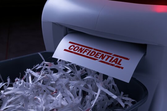 A shredder destroying a white document with red CONFIDENTIAL text, strips of paper falling into the bin, moody dramatic office lighting