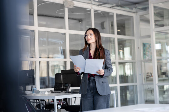 Young woman holding documents in hands and looking contented