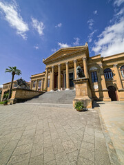 Obraz premium Neoclassical facade of Teatro Massimo opera house in Palermo, Sicily, shot from a low right angle perspective. Features the grand stone staircase, bronze lions, and a tall palm tree.
