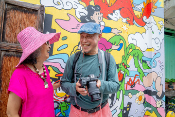 Couple enjoys time together while taking photos in front of colorful mural in an urban area © Hip.hub