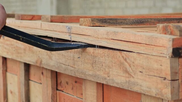 Opening a wooden crate using crowbar and hammer for delivery