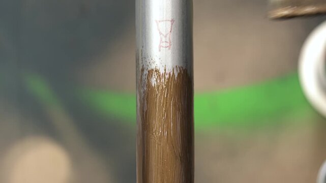 A decorator paints a metal broomstick pipe, using a special paint to create a wood grain effect.