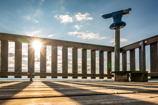 wooden pier with mountains in the distance, reflecting on calm water in the early morning light