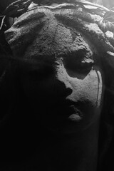 Fototapeta premium A weathered cemetery angel emerges from darkness, reminding us that even in grief, hope quietly endures.