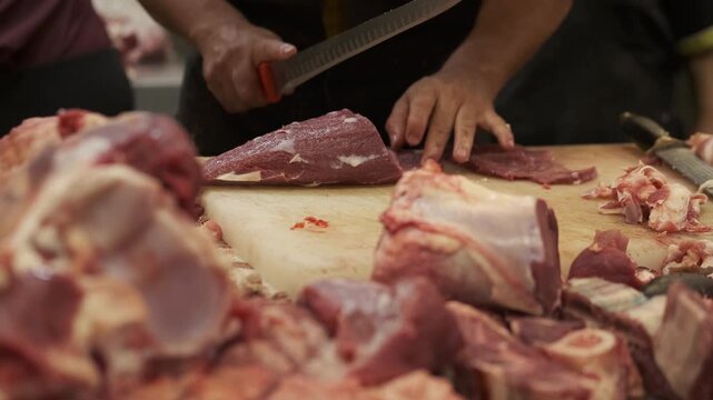 Close-up of a butcher trimming fresh raw beef with a sharp knife at a traditional Mexican market. Professional meat preparation and butchery process.