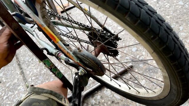 Close-up of a mechanic using a wrench to loosen the axle nut on a bicycle wheel.