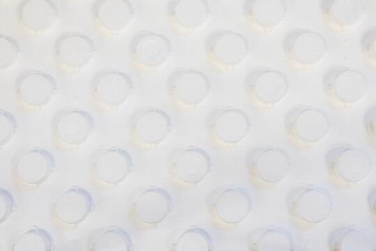 Top view macro texture of a white polystyrene underfloor heating insulation panel with circular knobs