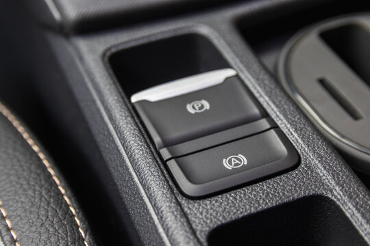 Close-up of an electronic parking brake and auto hold button on a modern car center console