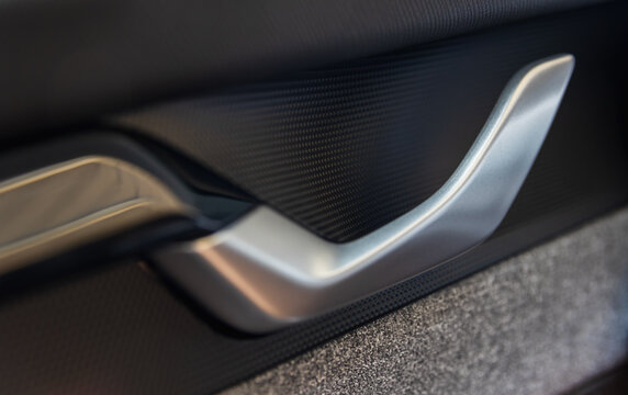 Close-up of a modern matte silver car door handle inside the luxury vehicle cabin