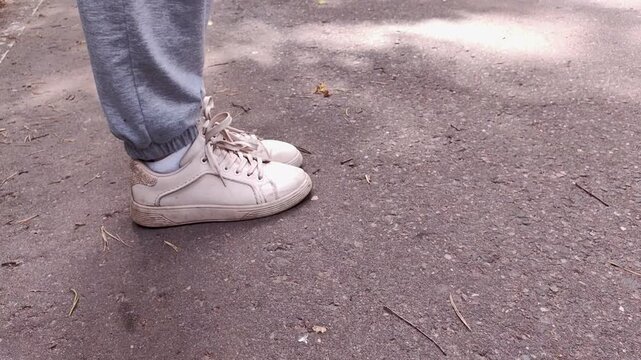 Close-up of a white sneaker walking on an asphalt road, casual footwear, outdoor lifestyle, urban detail.