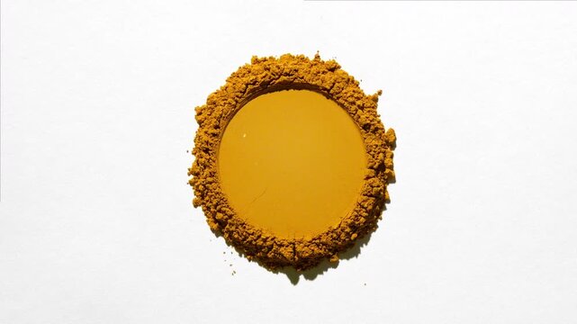 Top angle shot of a stack of yellow powder with a circular trace on a pale grey background highlighted by orbiting light creating changing shadows | Bee pollen concept