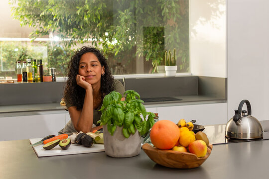 Relaxed woman reflecting in bright modern kitchen with fresh ingredients