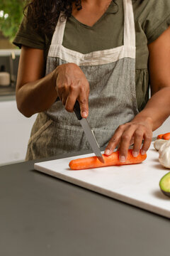 Close up of hands cutting carrot on wooden cutting board