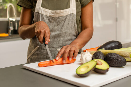 Close up of hands slicing fresh carrot for healthy cooking