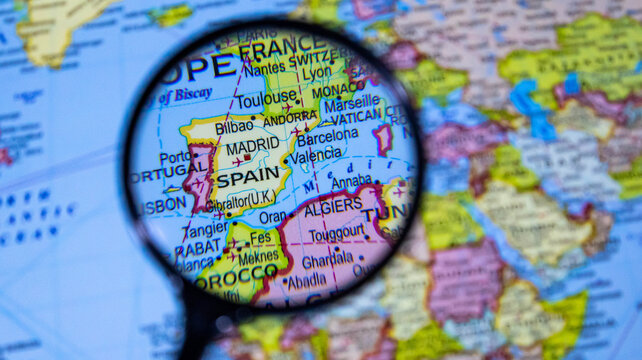 A close up view of spain on a political map, seen through a magnifying glass.