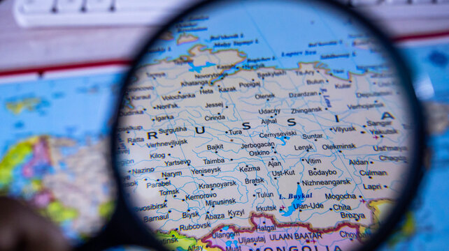 Magnifying glass on world map focusing on russia and surrounding countries in eurasia.