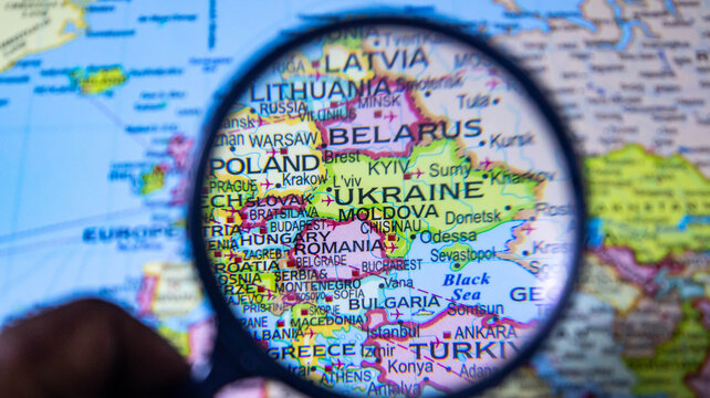 Magnifying glass focused on map of europe showing ukraine and surrounding countries.