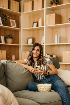 Young woman relaxing on sofa using smartphone