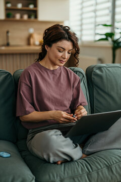 Woman managing diabetes with lancet and laptop at home