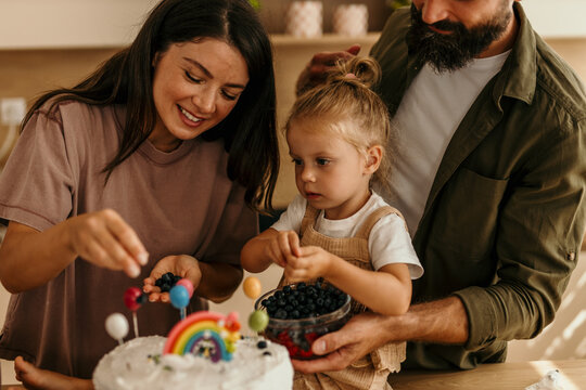 Family decorating birthday cake preparing for celebration