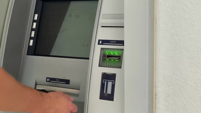 Close-up of a person inserting a credit card into an ATM slot for banking transaction