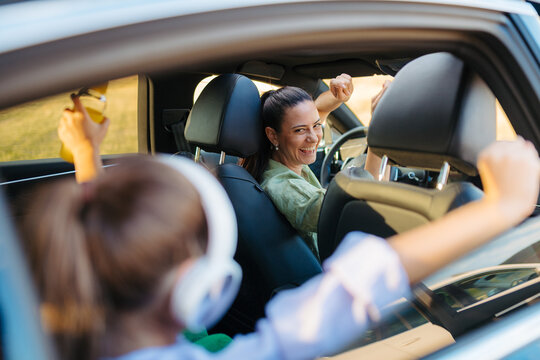 Young mother and her daughter having fun in their electric car.
