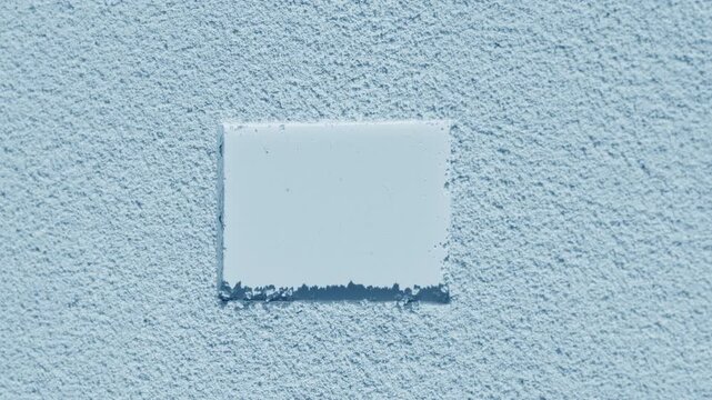 Top-to-bottom curved shot of pale blue smooth sifted powder with a rectangle imprint, highlighted by rotating directional light forming changing shadows