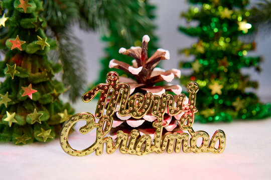 Letters and a pine cone against a background of Christmas trees