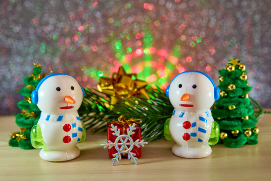 Unusual snowmen and a snowflake with a gift near a Christmas tree branch