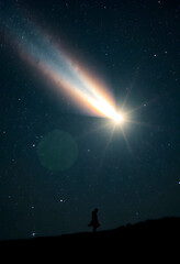 Fototapeta premium Silhouette of person watching bright comet in starry night sky