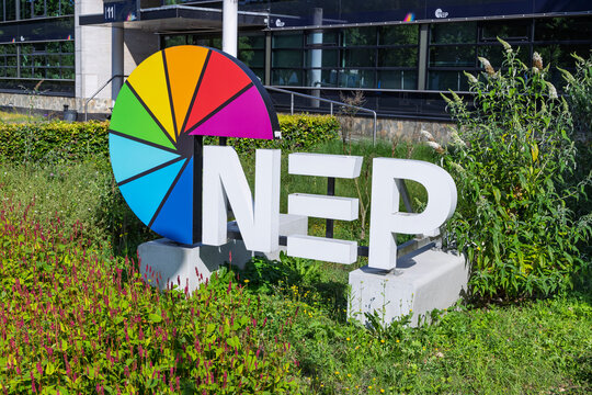 Hilversum, Netherlands - July 13, 2026: The white letters and multicolored wheel logo of NEP Group, a global media technology company, placed in a garden outside their studio building.