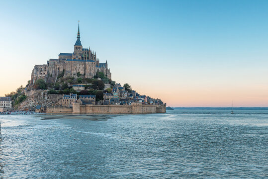 Mont Saint-Michel Abbey during high tide surrounded by the sea with medieval architecture and scenic coastal landscape at sunset in Normandy, France. Tidal island with monastery in Normandie