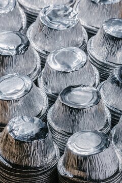 Stack of empty aluminum foil cupcake liners. Shiny metallic baking cups for dessert preparation. Metal waste for recycling and household supplies. Industrial kitchen utensil concept.