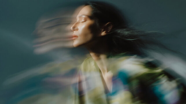 A woman poses in profile with closed eyes, captured with dynamic motion blur creating an abstract effect.