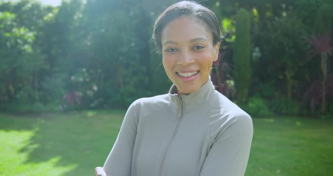 Woman posing in yard resting chin, folding arms wearing gray jacket smartwatch, sunlight softening